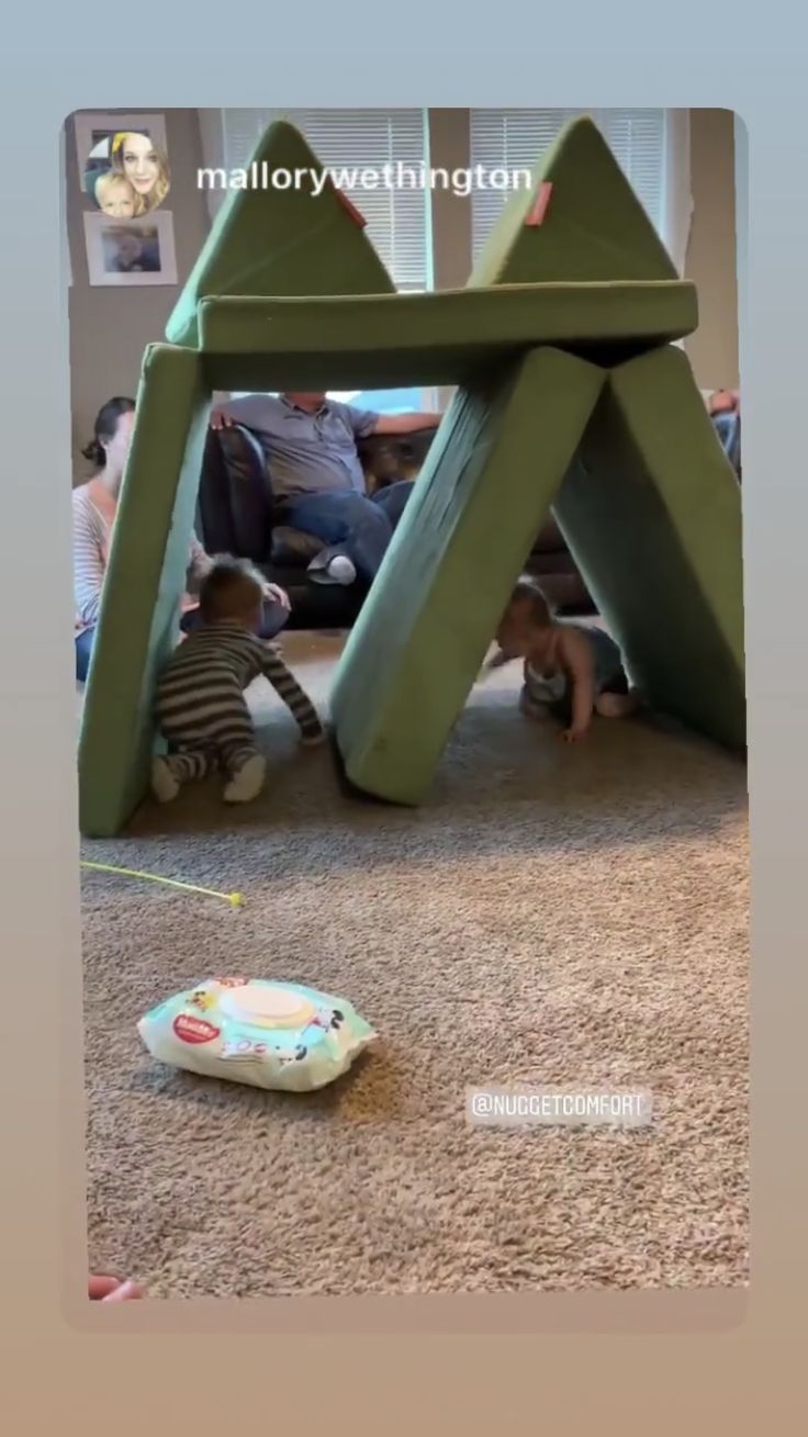 two children are playing in the living room under a green tent with mountains on it