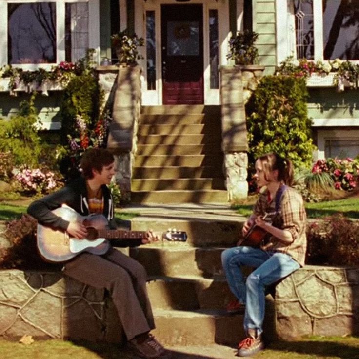 two people sitting on steps playing guitar and singing into each other's ears with the caption in spanish