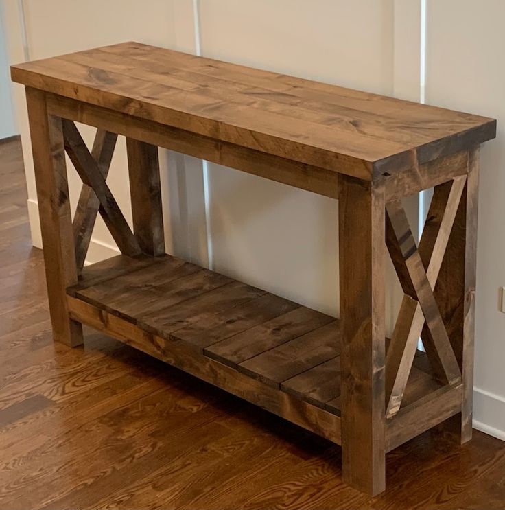 a wooden bench sitting on top of a hard wood floor next to a white wall