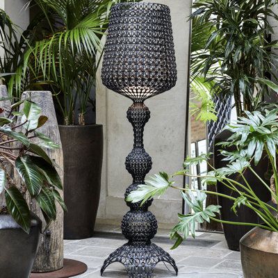 a tall metal lamp sitting next to potted plants