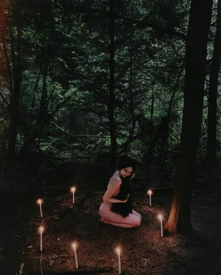 a woman sitting on the ground surrounded by candles