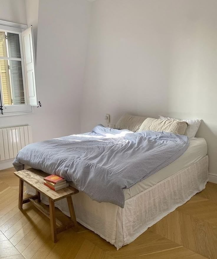 a bed sitting on top of a wooden floor next to a window