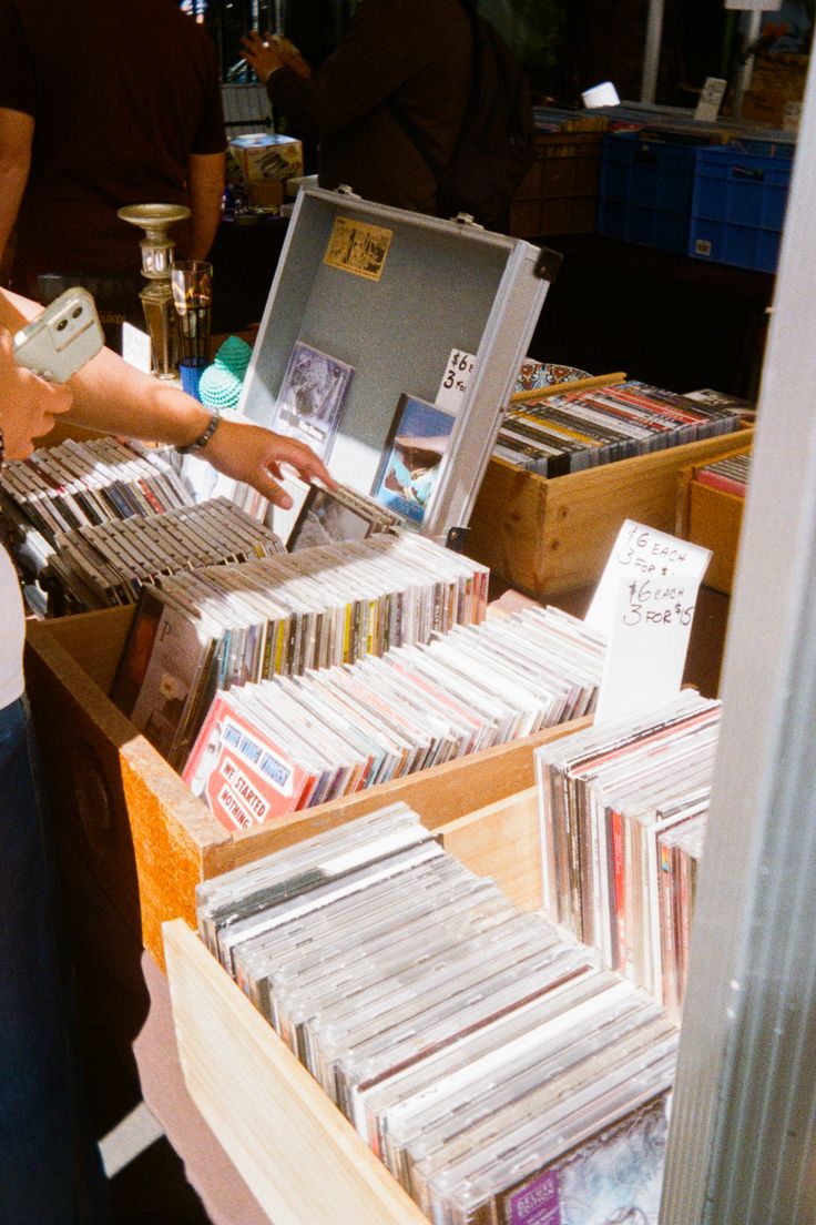 a woman standing in front of a table filled with lots of cd's and cds