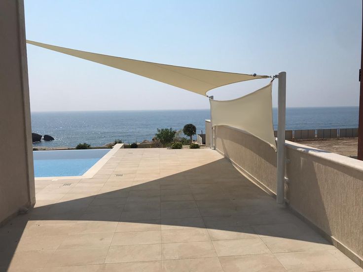 an outdoor area with a swimming pool and shade sail on the wall next to it