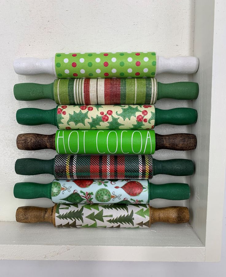 a stack of rolled up christmas wrappings on top of a white shelf next to a wall