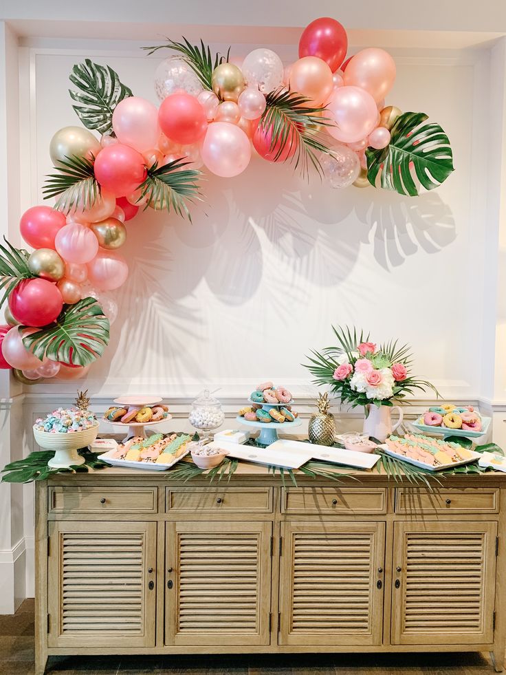 a buffet table filled with lots of food and balloons in the shape of palm leaves