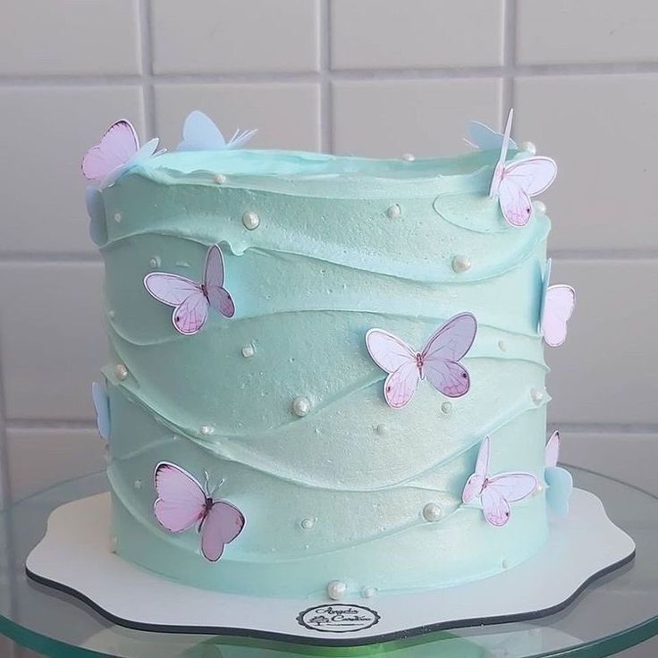 there is a blue cake with pink butterflies on the top and white icing around it