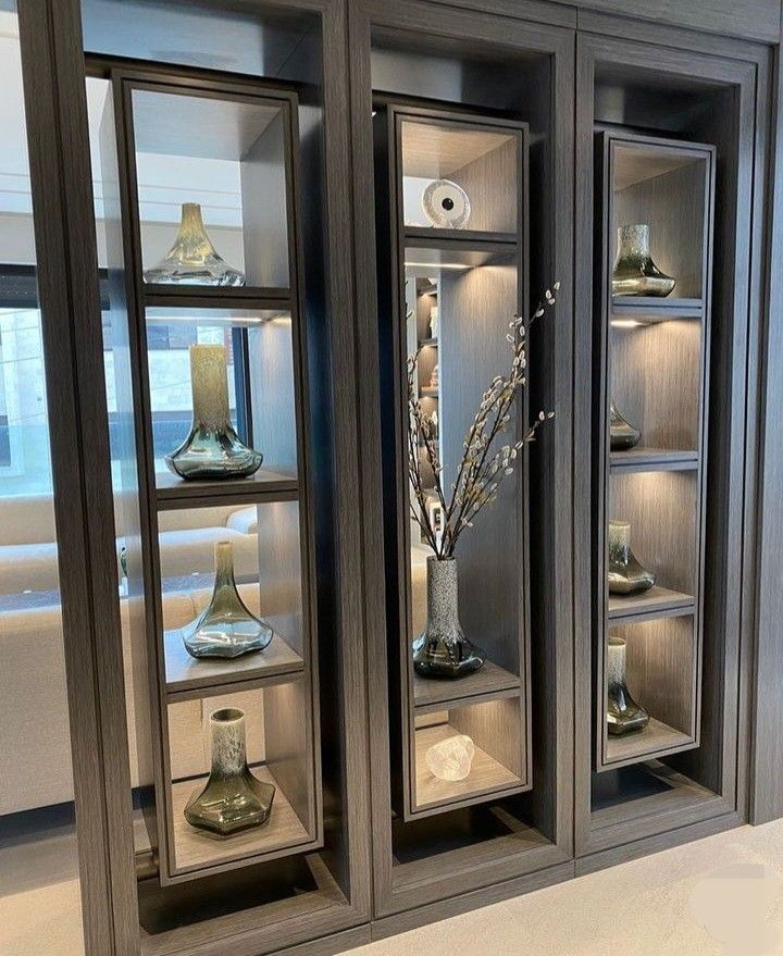 two glass cabinets with vases and candles in them