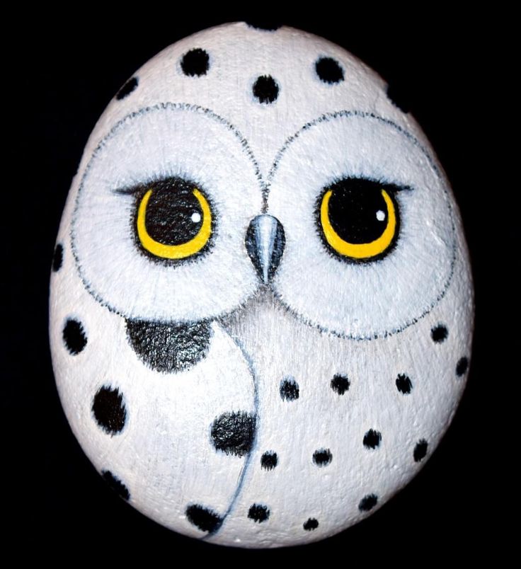 an owl painted on a rock with yellow eyes