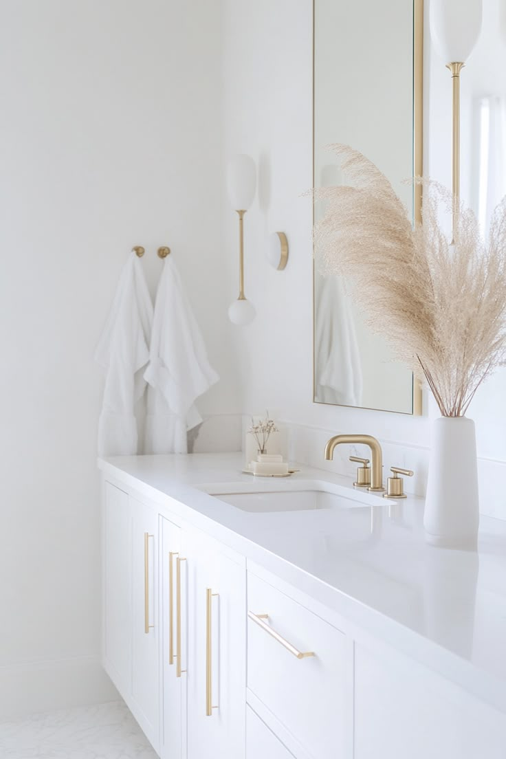 a white bathroom with gold accents and mirrors