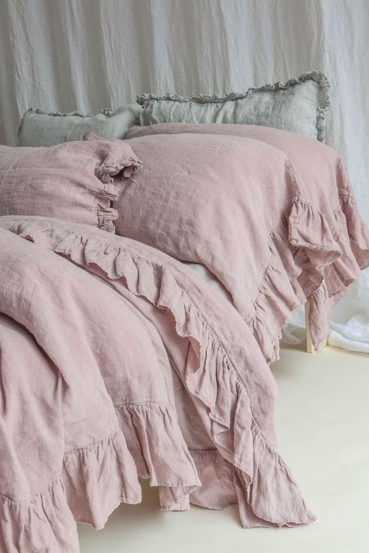 a bed with pink linens and ruffled pillows