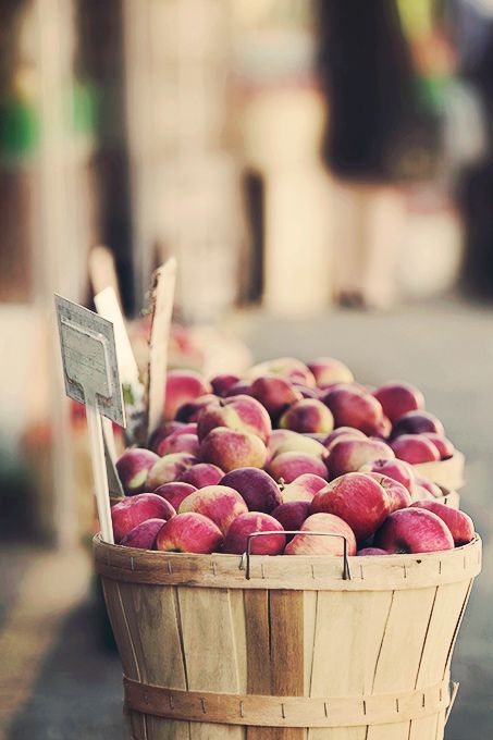 a basket filled with lots of red apples on top of a street next to a building