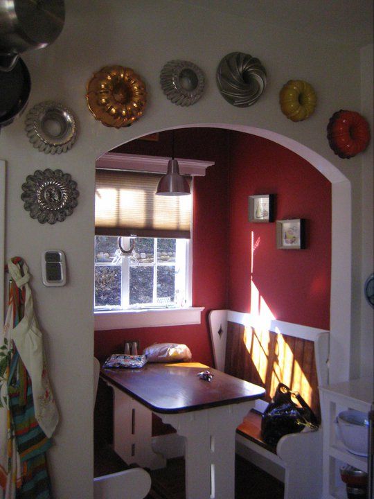 a kitchen area with a table, chairs and plates on the wall