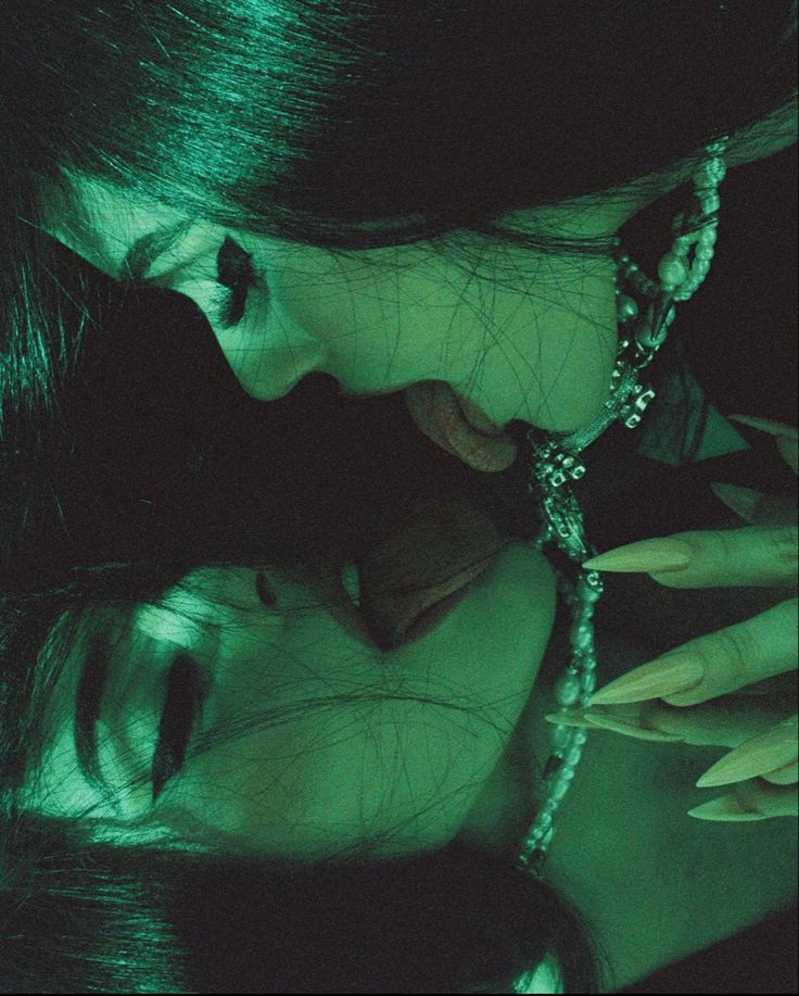 two women with dark hair and green eyes are touching each other's foreheads