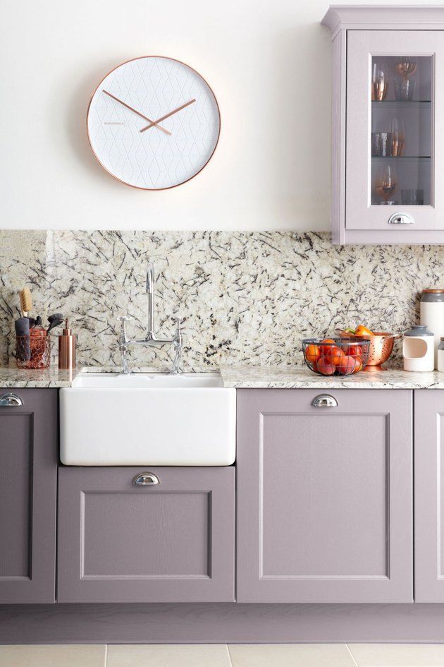 a kitchen with gray cabinets and a white clock on the wall