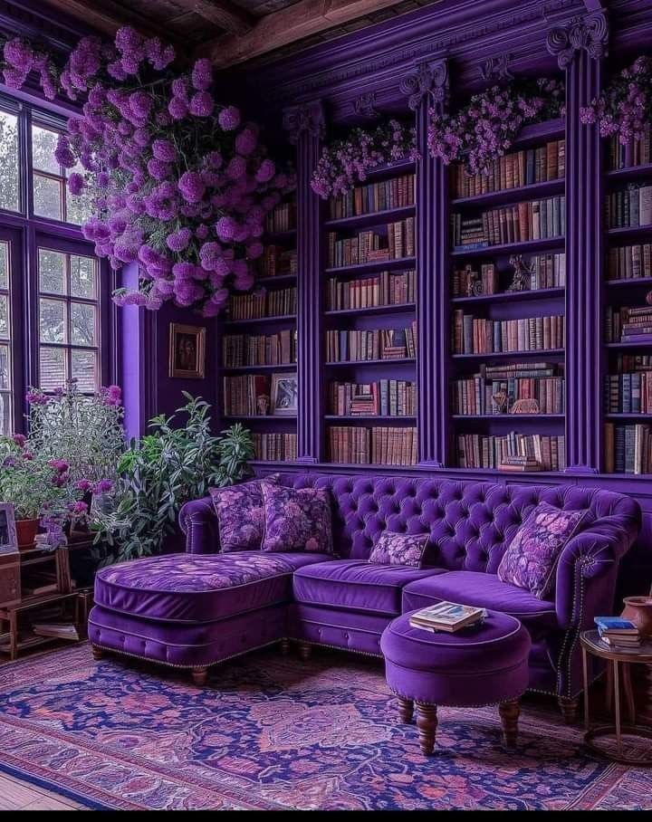 a living room filled with purple furniture and lots of books on the shelves next to a window