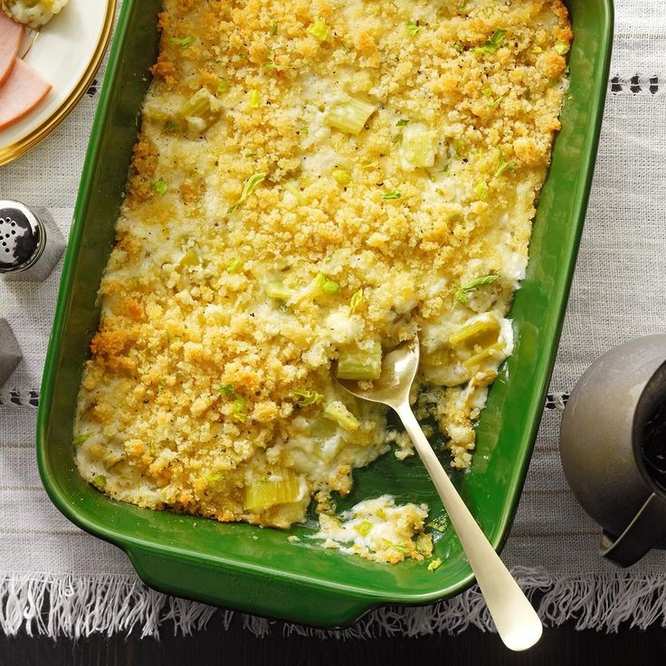 a green casserole dish filled with meat and vegetables