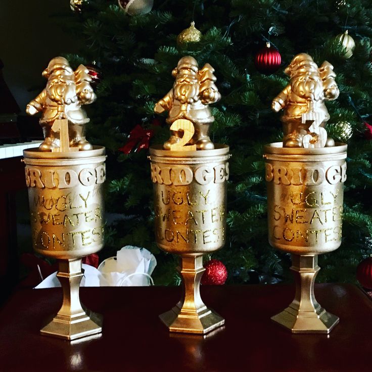 two golden goblets sitting on top of a table next to a christmas tree