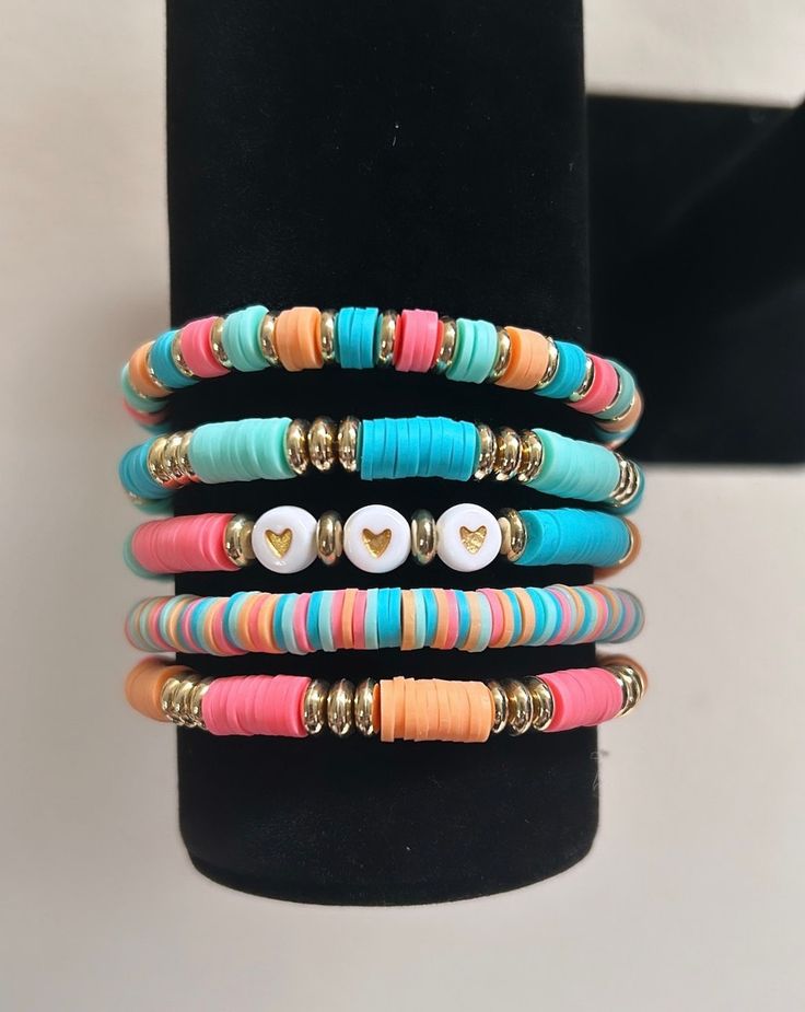 multicolored bracelets with buttons and gold accents on a black display stand in front of a white background