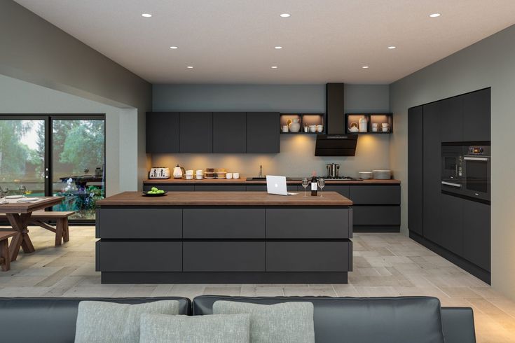 a modern kitchen with an island counter top and dark gray cabinets, along with wooden dining tables