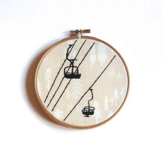 a cross stitch pattern with a ski lift in the background and pine trees behind it