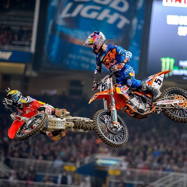 two motorcyclists in the air doing stunts on dirt bikes at a sporting event