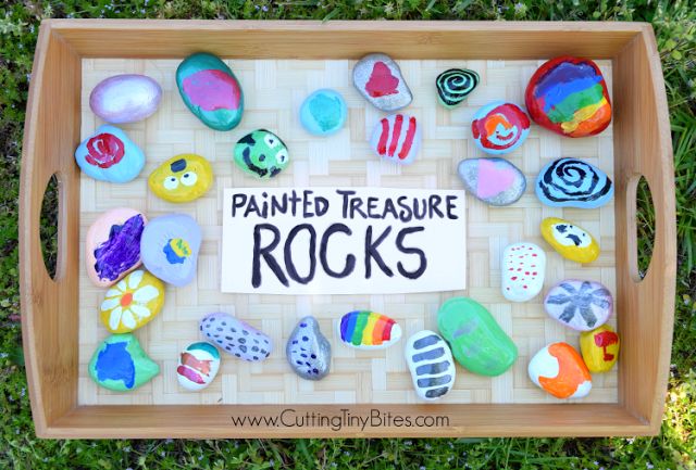 a wooden tray with painted rocks on it and the words painted treasure rocks written in black