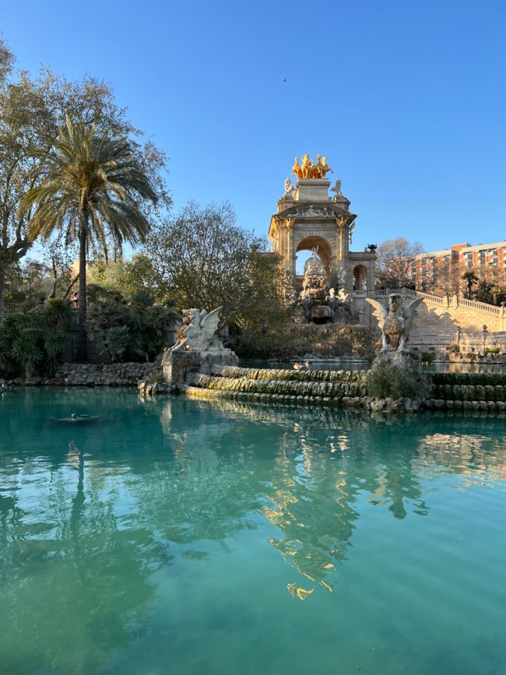 a large body of water next to a building and palm trees in the foreground