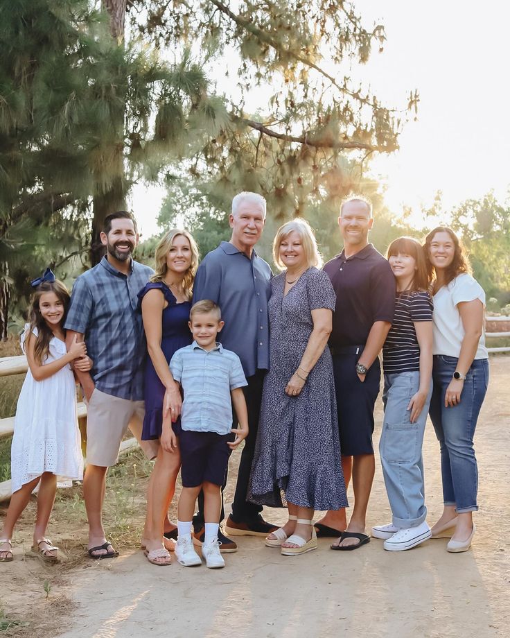 a group of people standing next to each other in front of a fence and trees