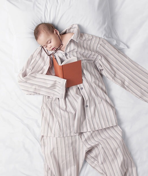 a baby is sleeping on a bed with a book in it's arms and head