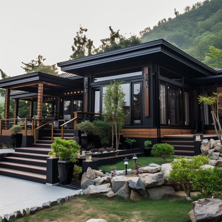 a black house with steps leading up to it's front door and landscaping area