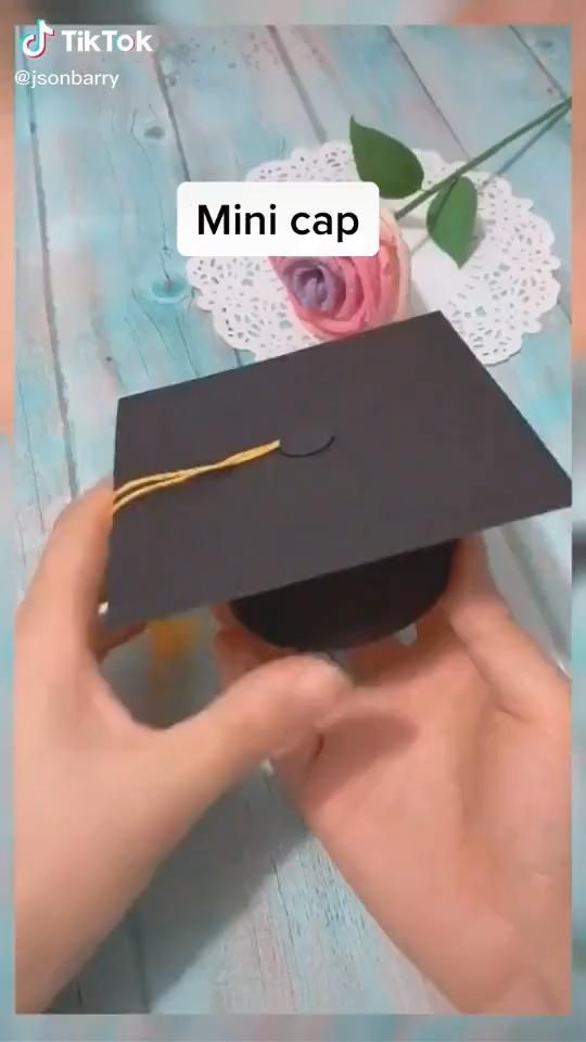 a person holding a black graduation cap with a rose on it and the caption reads mini cap