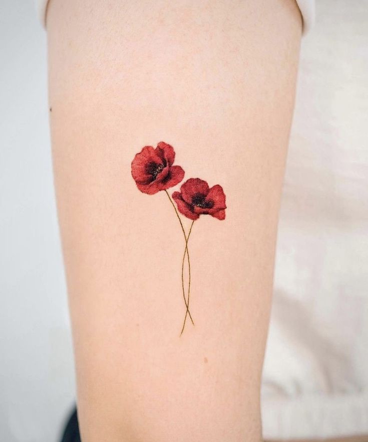 two red flowers on the back of a woman's right thigh, with one flower still attached