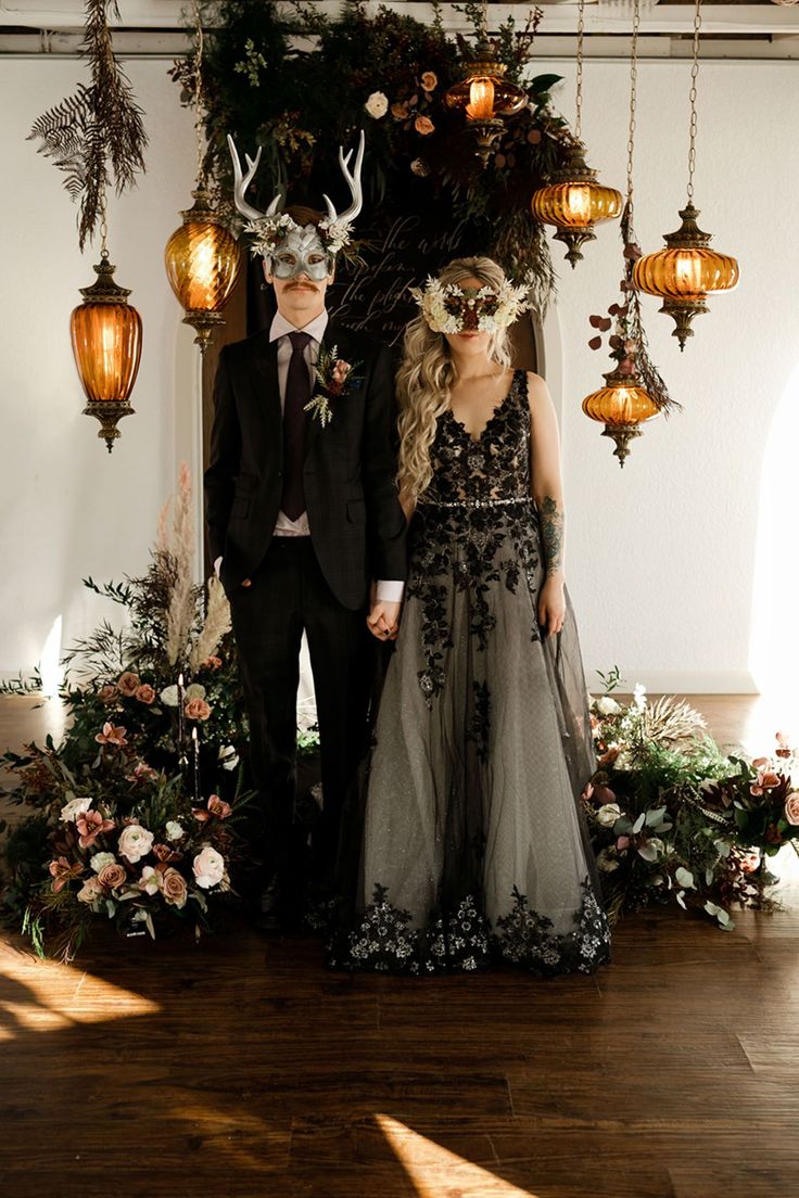 a man and woman standing next to each other in front of some hanging lights with deer heads on them