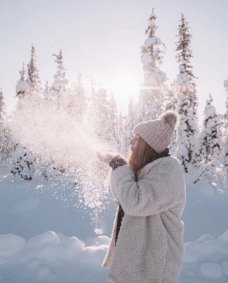 a woman standing in the snow blowing snow