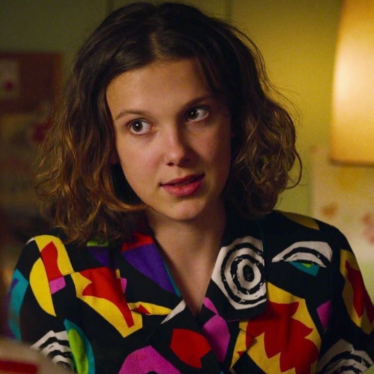 a woman in a colorful shirt looking at the camera with an intense look on her face