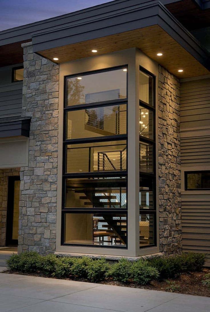 a modern house with stone and glass walls, stairs leading up to the second floor