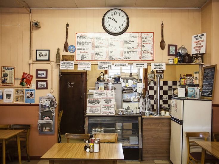 the inside of a restaurant with tables, chairs and a clock hanging on the wall