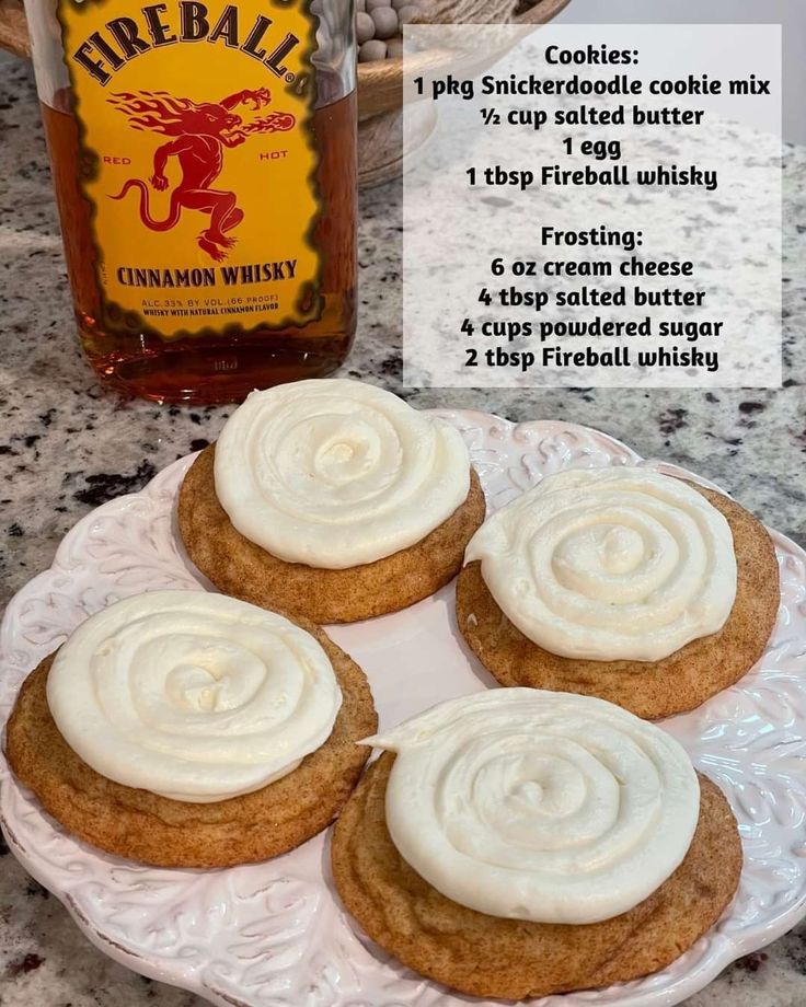 four cookies with frosting on a plate next to a bottle of fireball whiskey