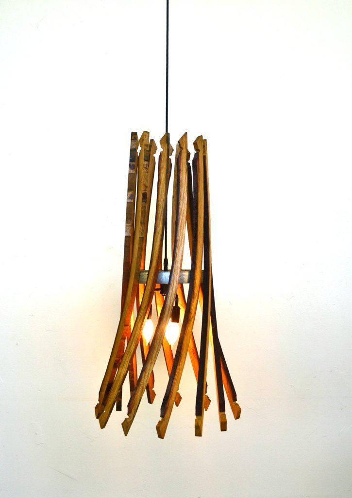 a light fixture made out of sticks hanging from a ceiling hook on a white wall