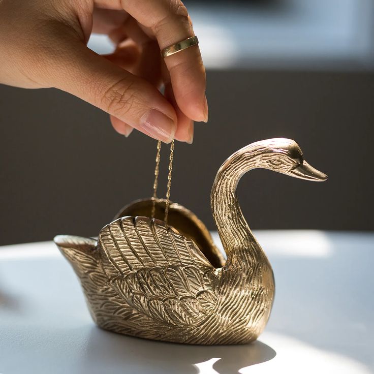 a gold swan ornament being held by a woman's hand