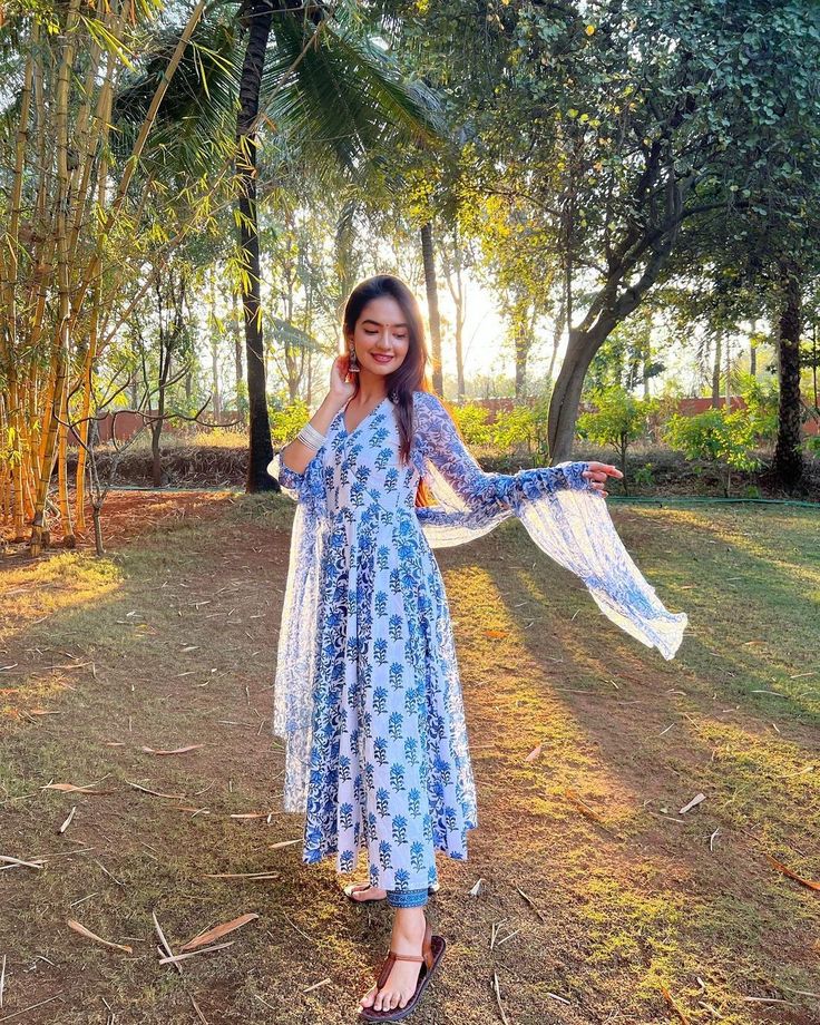 a woman in a blue and white dress posing for the camera