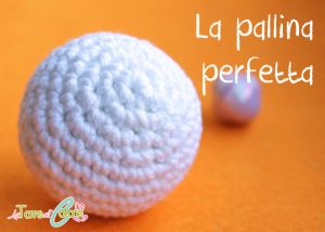 a white crocheted ball sitting on top of an orange surface with the words la palling perfetta