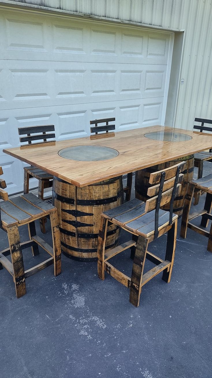 a wooden table and chairs made out of wine barrels are sitting in front of a garage door