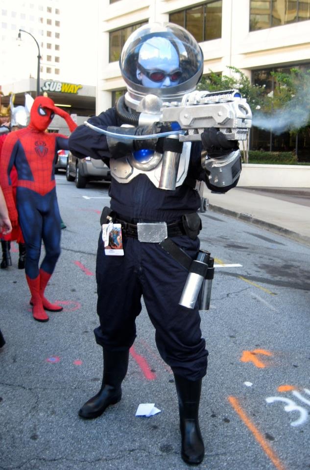 a man dressed up as spider - man on the street with other people in costume