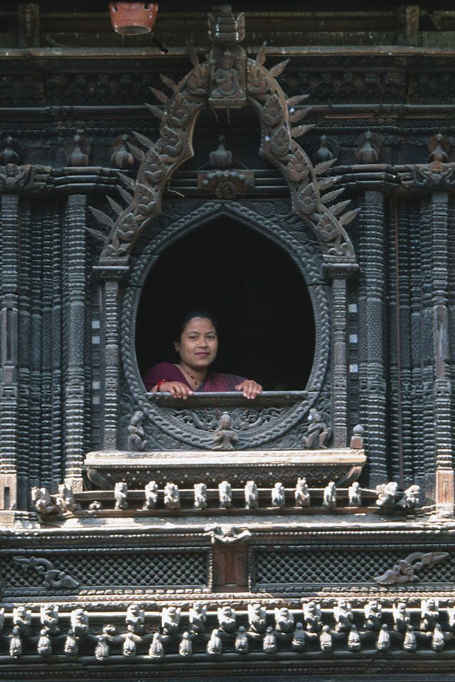 a woman is looking out the window of an ornately decorated building with intricate carvings