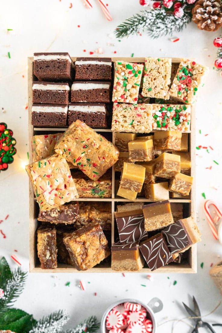 a wooden box filled with lots of different types of desserts and candy canes