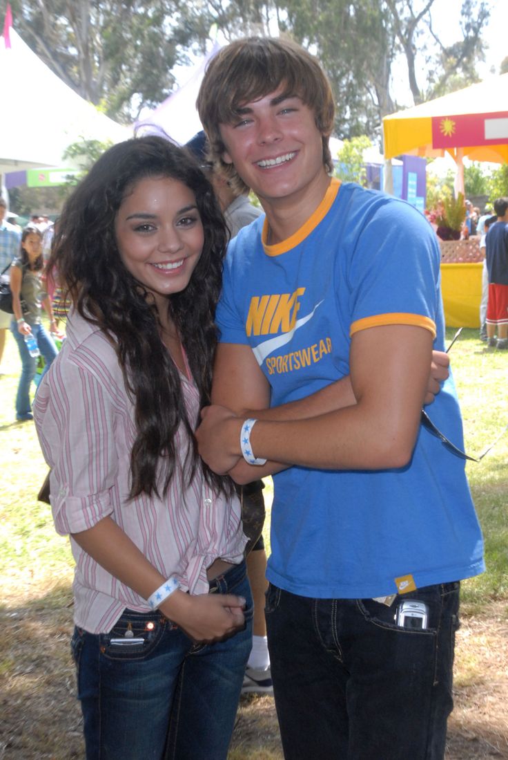 a young man and woman standing next to each other in front of a carnival tent