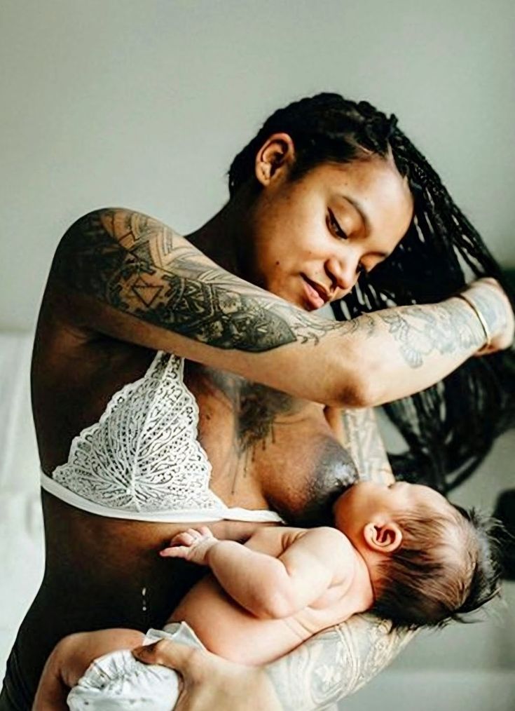 a man holding a baby in his arms while he is wearing a white bra top