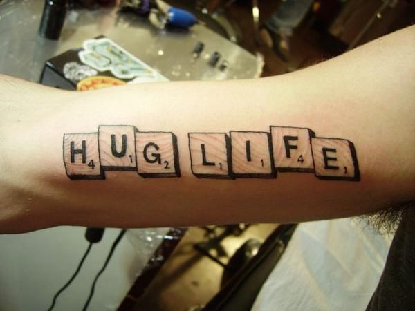 a person's arm with the word hug life spelled in scrabble letters